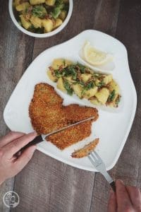 Kartoffelsalat mit grünem Spargel und Speck beim Essen auf dem Teller