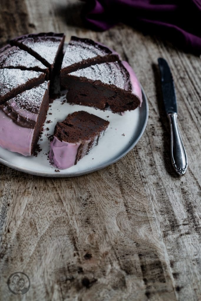 Stück Rotweinkuchen mit rosa Rotweinguss auf dem Teller