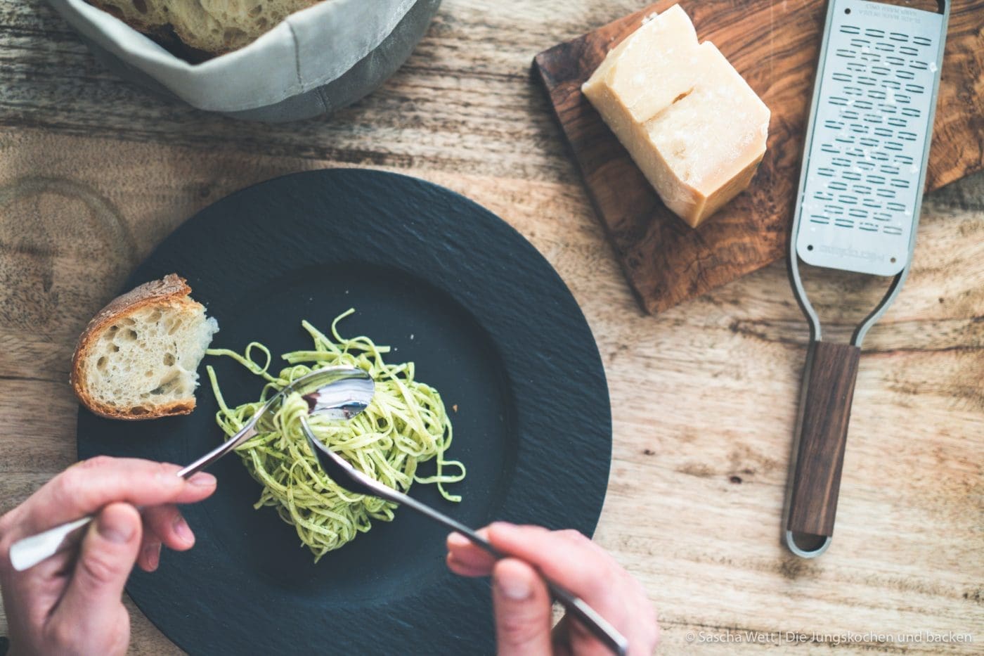 Pasta al pesto 15 Spaghetti auf Teller. Spaghetti werden mit Gabel und Löffel aufgerollt