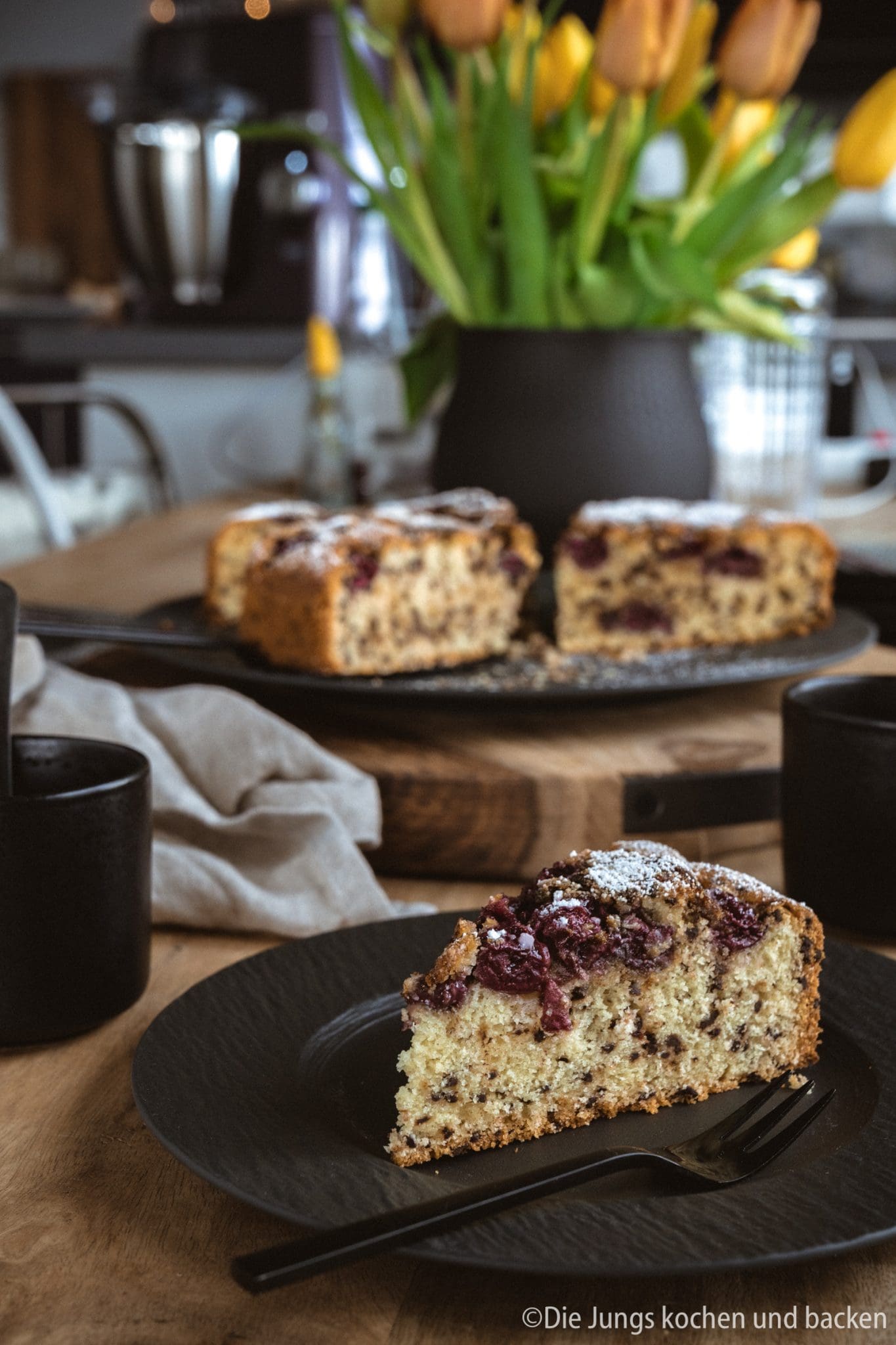 Versunkener Kirschkuchen auf dem Tisch. Angeschnitten im Vordergrund