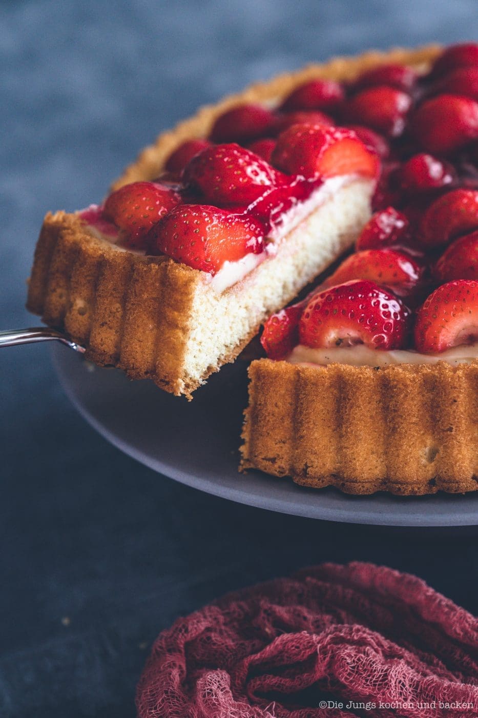 Erdbeerkuchen mit Pudding 5 | Heute kommen wir wieder mit einem schnellen Klassiker von zu Hause. Eine ganz klassischee Erdbeerkuchen mit Pudding. Ein simpler Obstboden mit etwas Puddingcreme und frischen Erdbeeren drauf. Das ist auch wieder so etwas, dass Oma Lore früher immer schnell mal so aus dem Nichts gezaubert hat. Immer dann, wenn entweder unangekündigter Besuch vor der Türe stand oder sie die Erdbeeren aus dem Garten verarbeiten wollte, damit sie sich nicht zu lange im Kühlschrank stapelten.