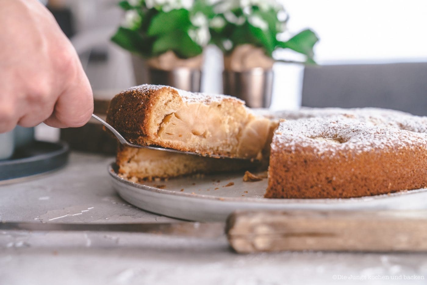 Versunkener Apfelkuchen nach Oma Lore. Saftig aus der Springform 3 Stück versunkener Apfelkuchen mit Puderzucker auf einem Teller