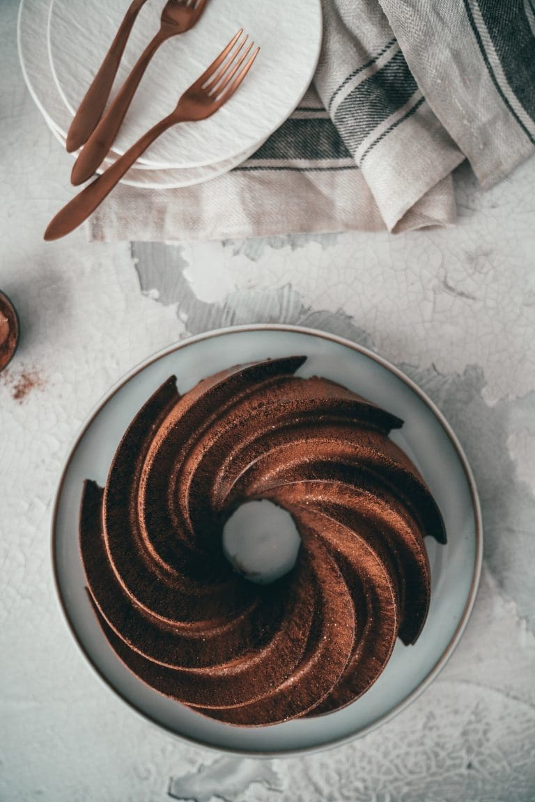 Zimt-Marmorkuchen mit Schokoglasur von oben, daneben Teller mit Kuchengabeln