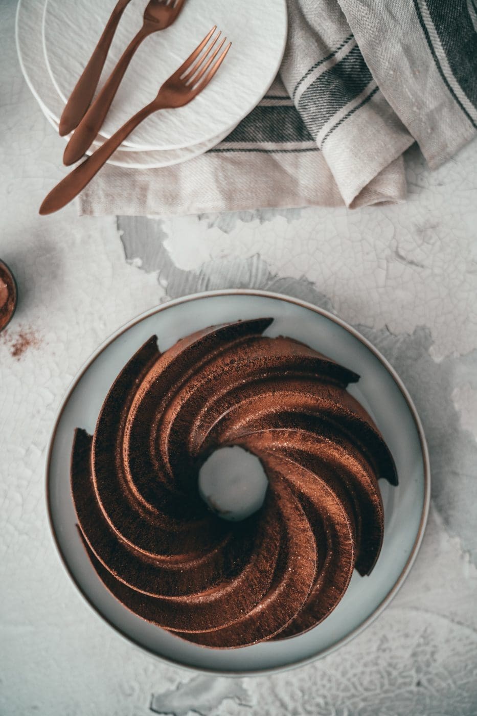 Zimt-Marmorkuchen mit Schokoglasur von oben, daneben Teller mit Kuchengabeln