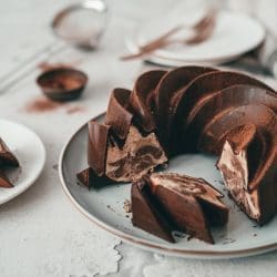 Angeschnittener Zimt-Marmorkuchen mit Schokoglasur, daneben Kuchenstücke auf Tellern