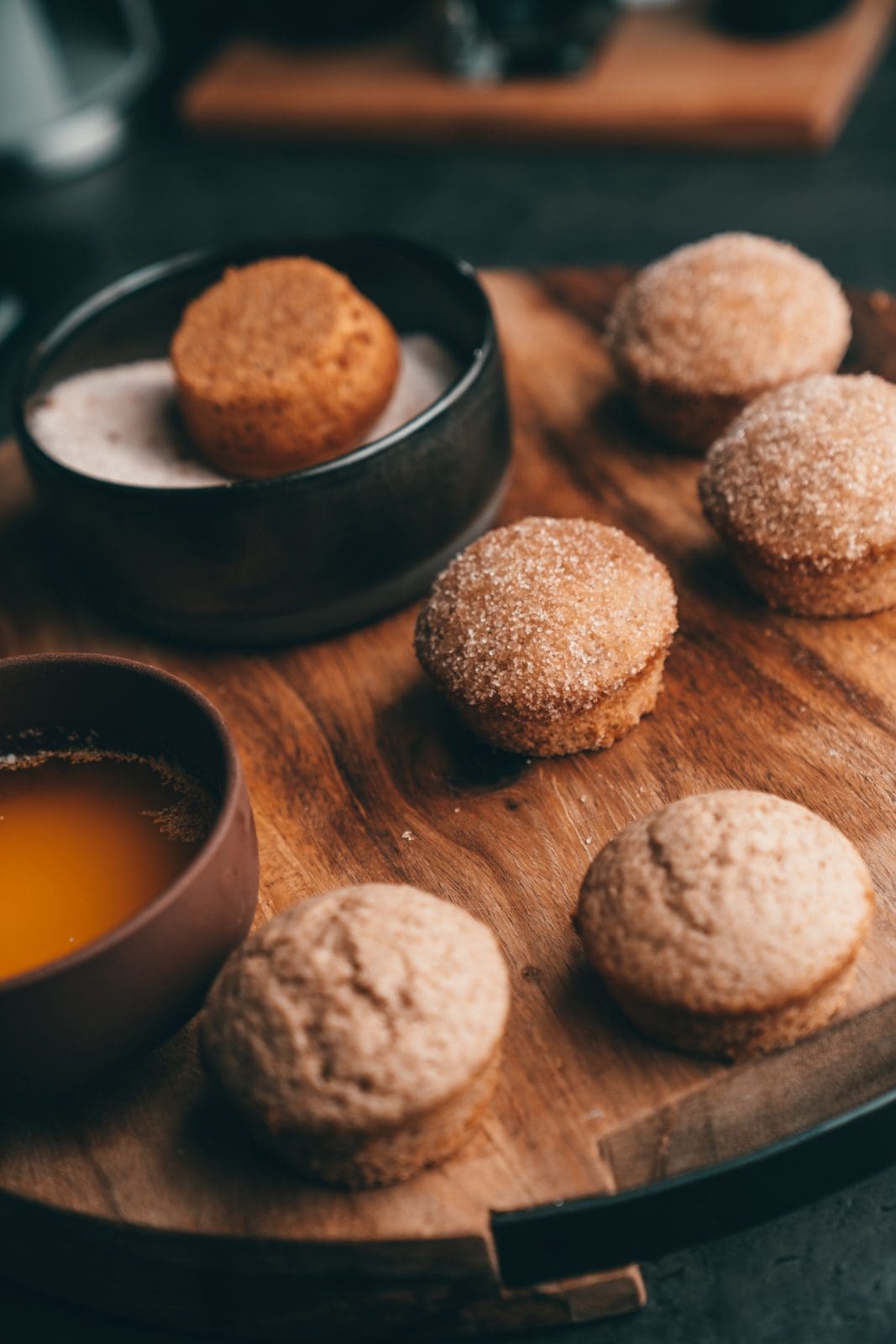 Gebackene Muffins neben Schalen mit geschmolzener Butter und Zimtzucker