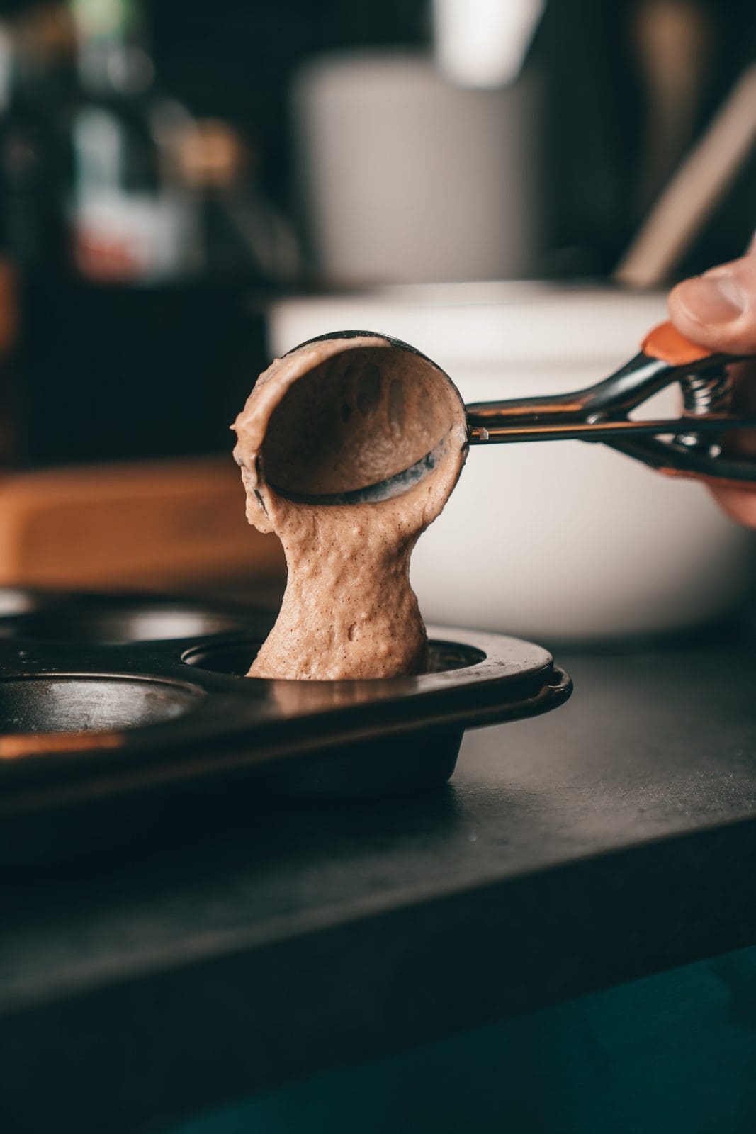 Muffinteig wird mit dem Eisportionierer in das Muffinblech gefüllt