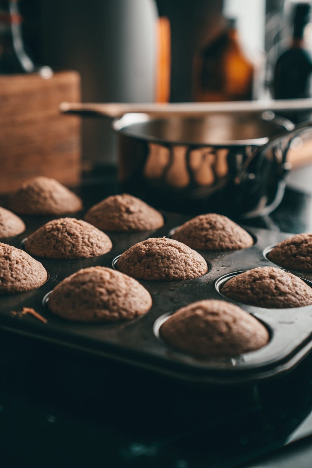 Frisch gebackene Muffins im Muffinblech, daneben geschmolzene Butter