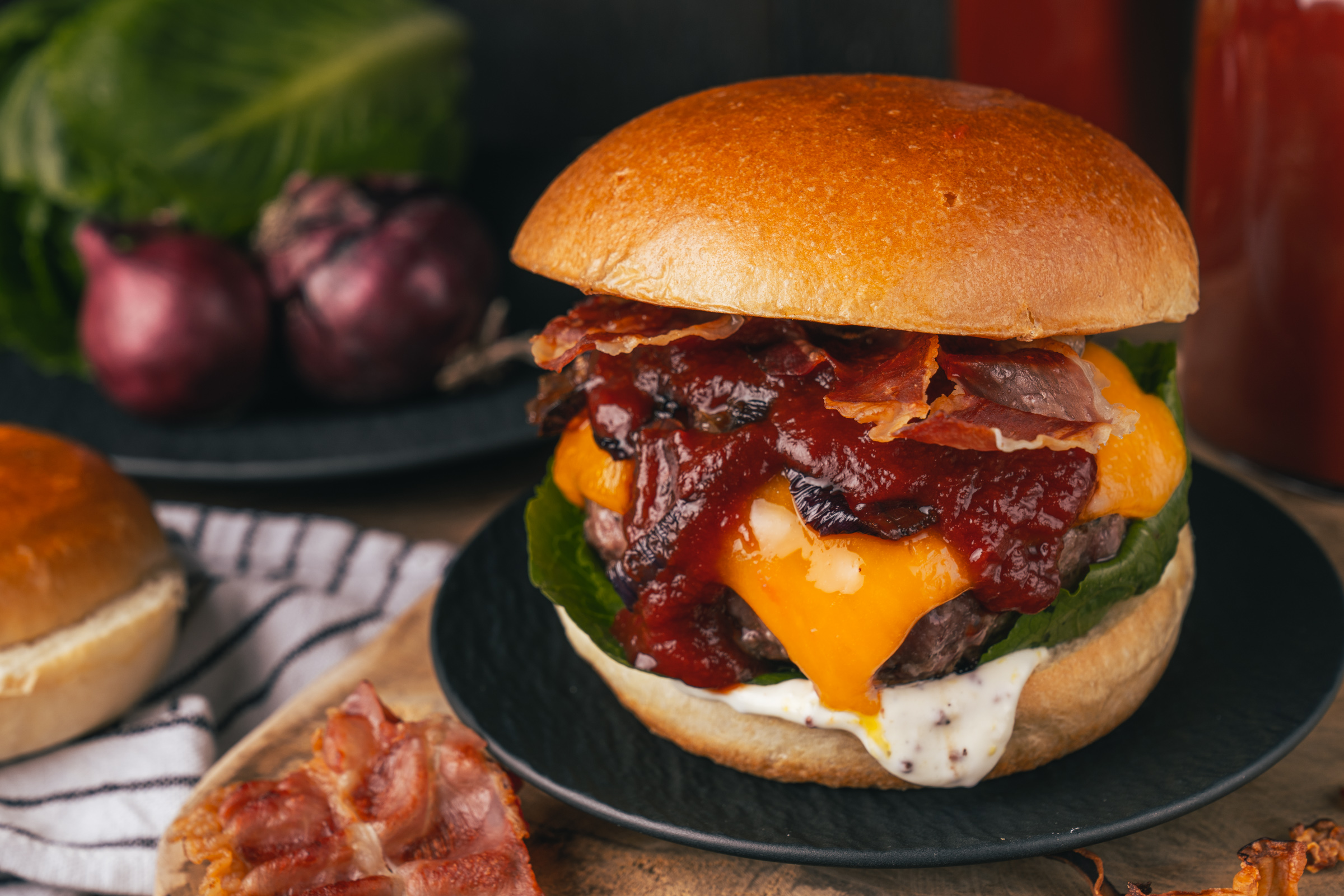 Rezept für einen klassischen BBQ-Cheeseburger, den wir mit einer dicken Scheibe Cheddar belegt haben. Getoppt von unserer BBQ-Sauce und Bacon, einfach perfekt.