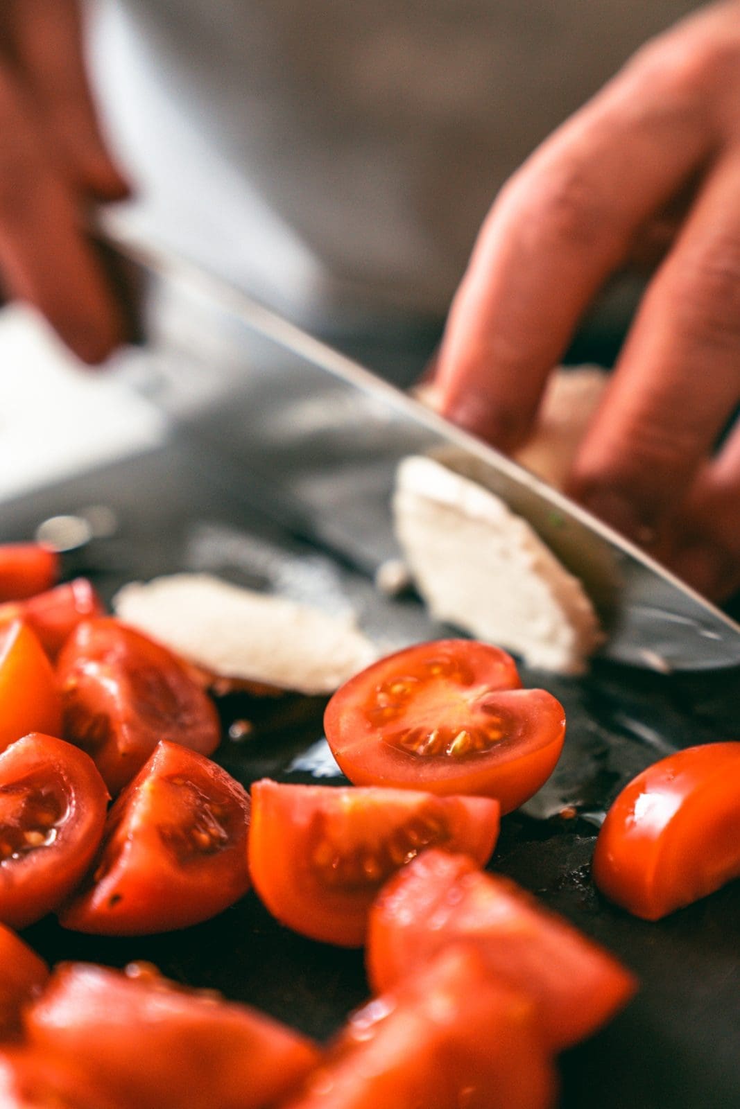 Tomaten auf dem Bettchen. Mozzarella wird geschnitten