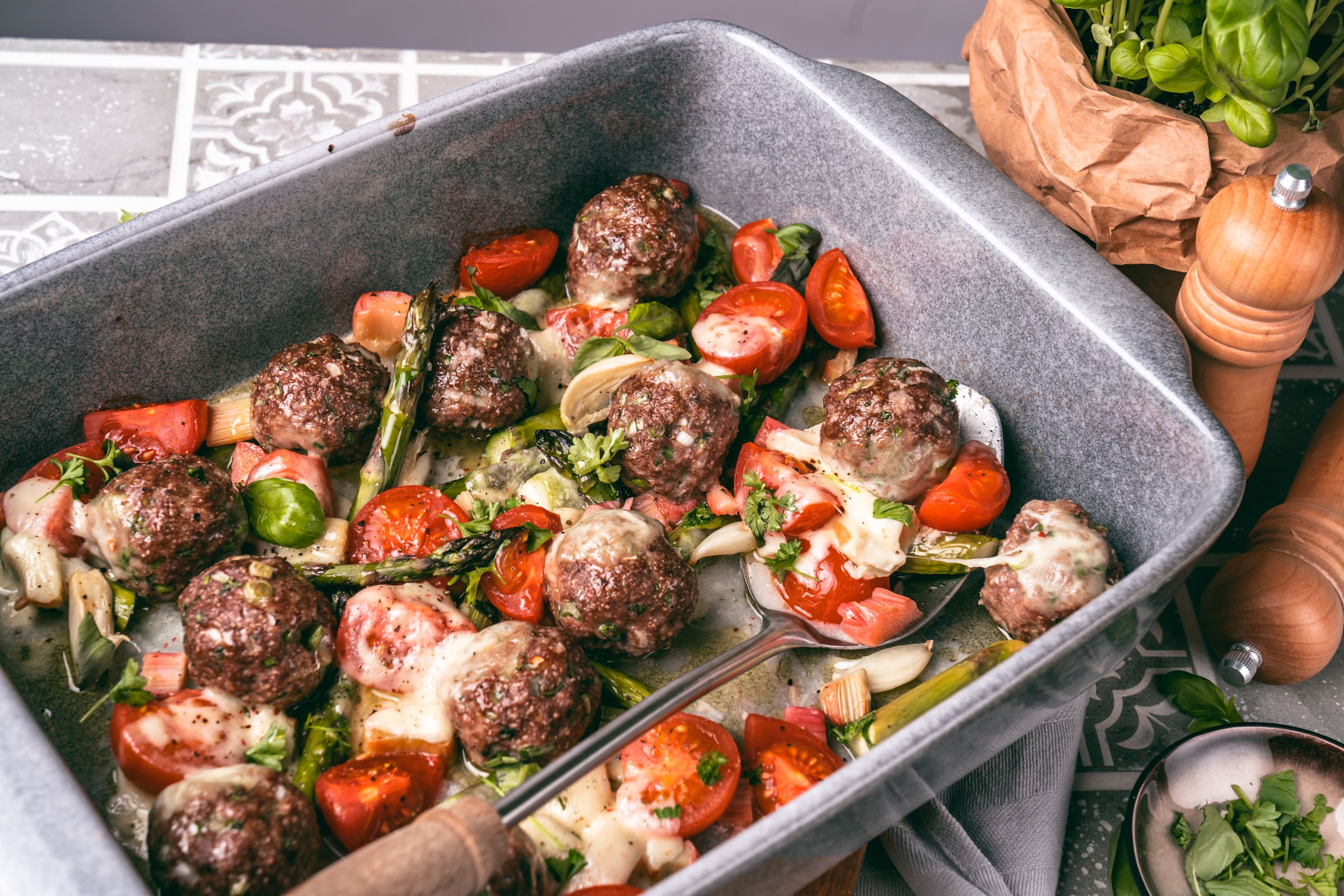 Hackbällchen mit Spargel und Rhabarber in der Auflaufform. Querformat