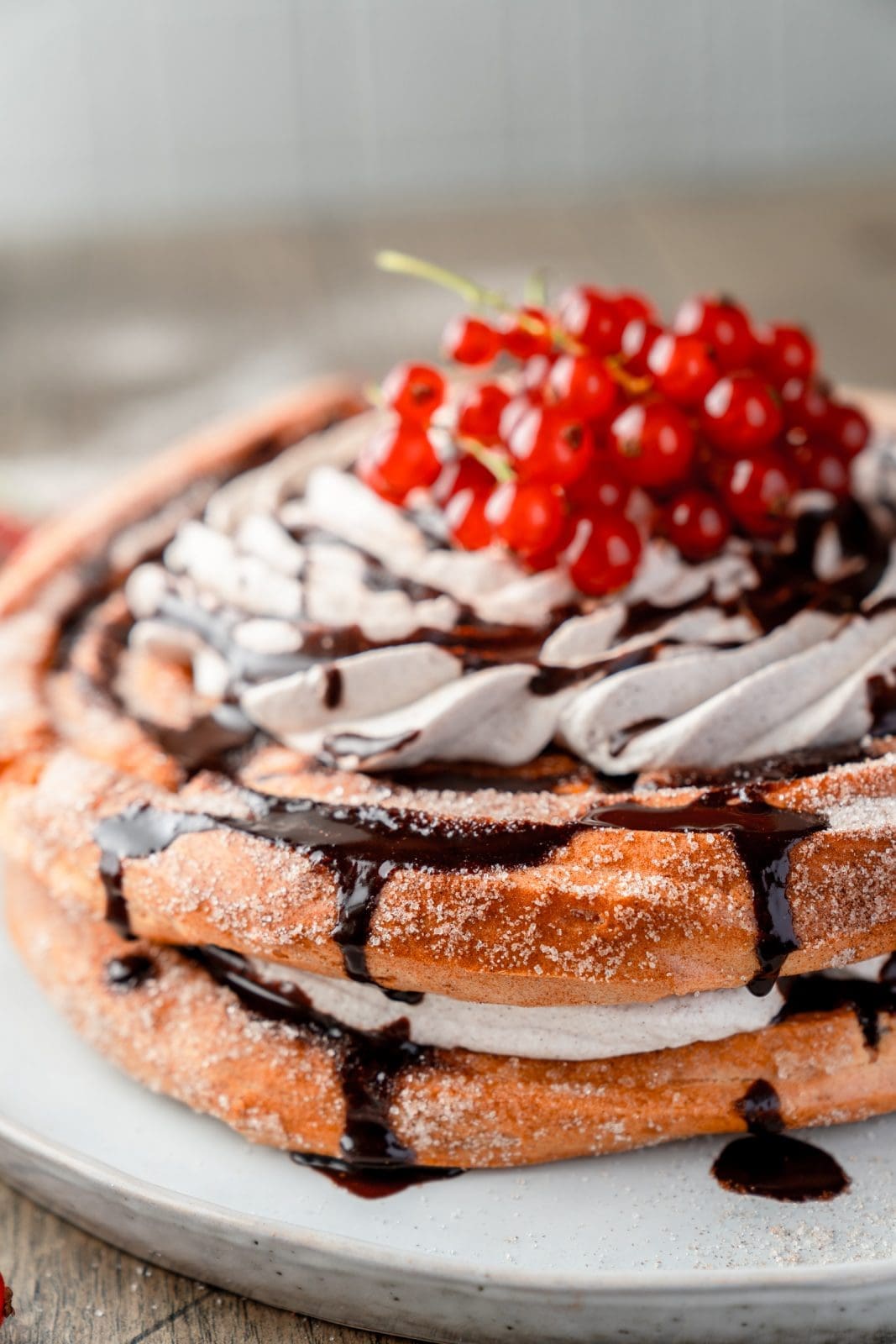 Seitenansicht der Churros-Torte mit zwei Brandteig-Böden in Zimt-Zucker