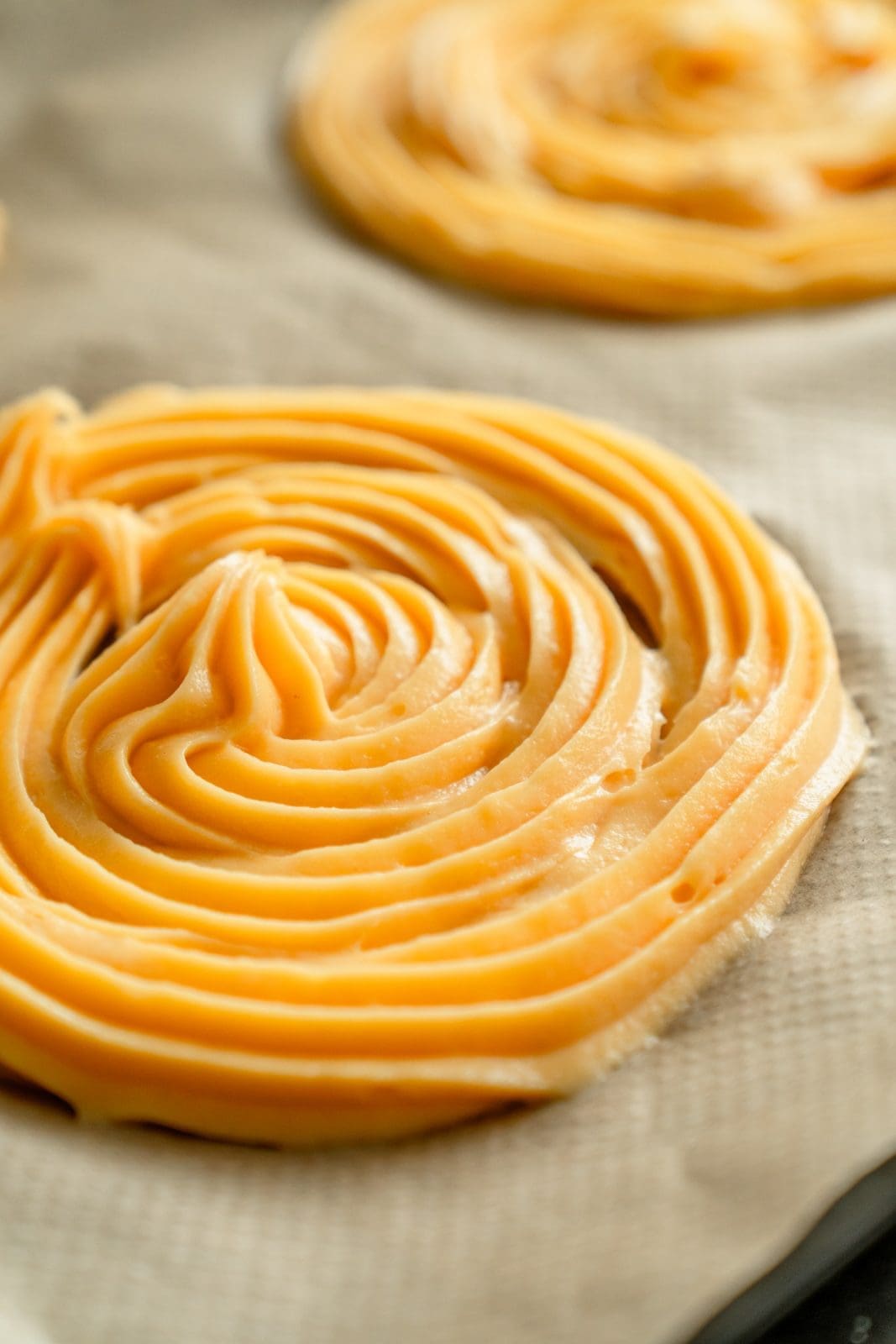 Gespritzte Brandteig-Spiralen für die Churros-Torte auf dem Backblech