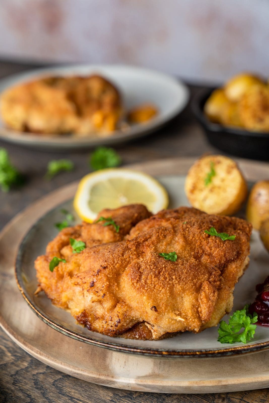 Cordon Bleu selber machen. Mit Senf-Knoblauch-Füllung aus der Pfanne 1 Cordon Bleu mit kleinen Kartoffeln, Zitronenspalte und Preiselbeeren auf dem Teller