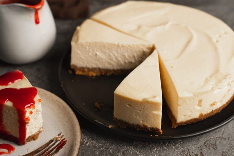 New York Cheesecake Rezept, cremiger Cheesecake angeschnitten mit Erdbeersauce