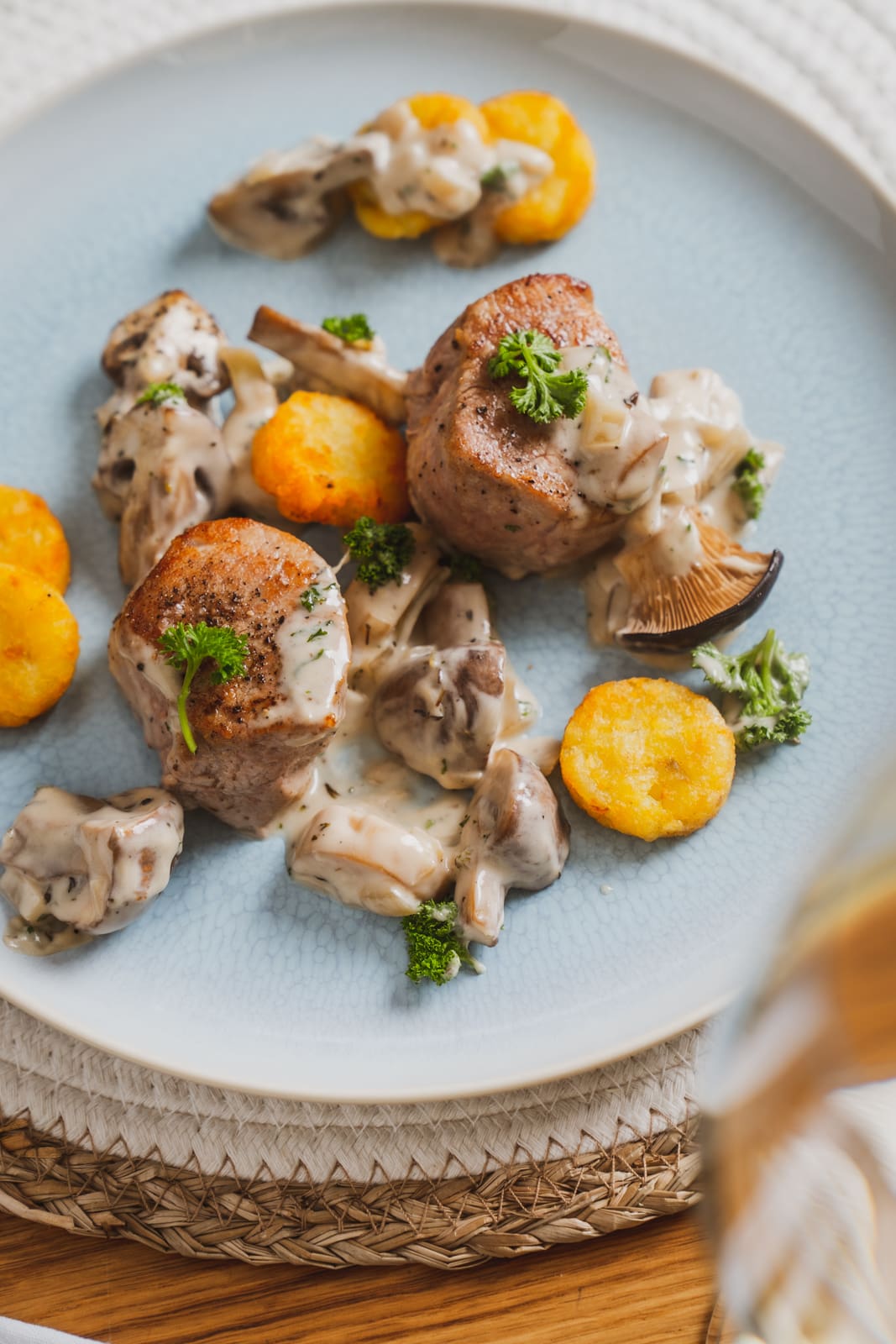 Schweinemedaillons mit cremiger Pilzrahmsoße und Rösti auf dem Teller