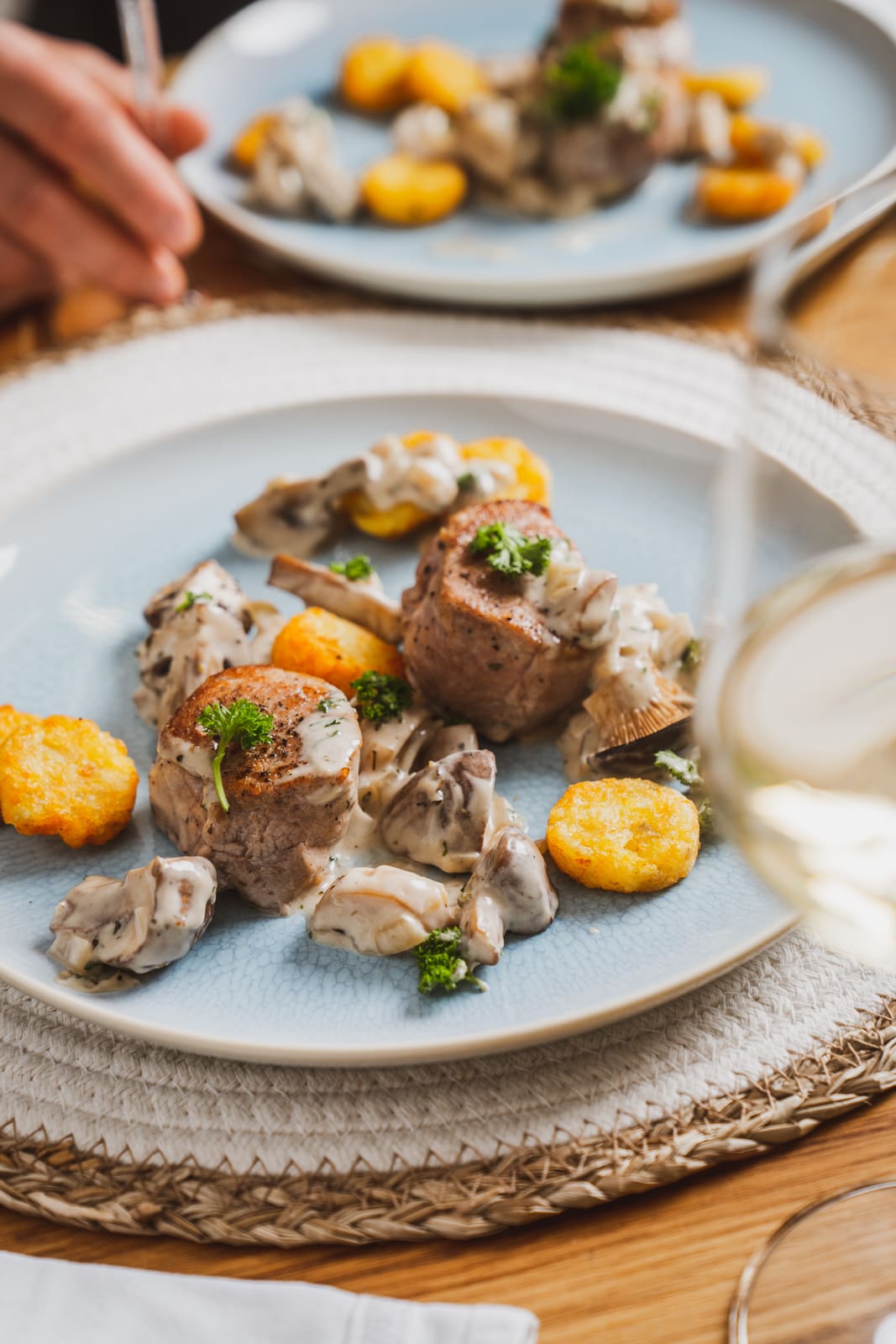 Teller mit Schweinemedaillons in Champignonrahmsoße und kleinen Rösti