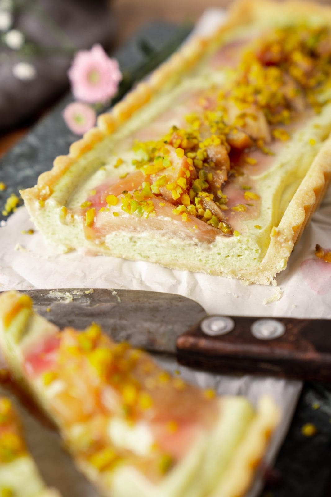 Pistazien-Tarte mit Rhabarber | Unser Frühlingskuchen mit Vermouth 7 Pistazien-Tarte mit Rhabarber angeschnitten auf dem Tisch in Nahaufnahme