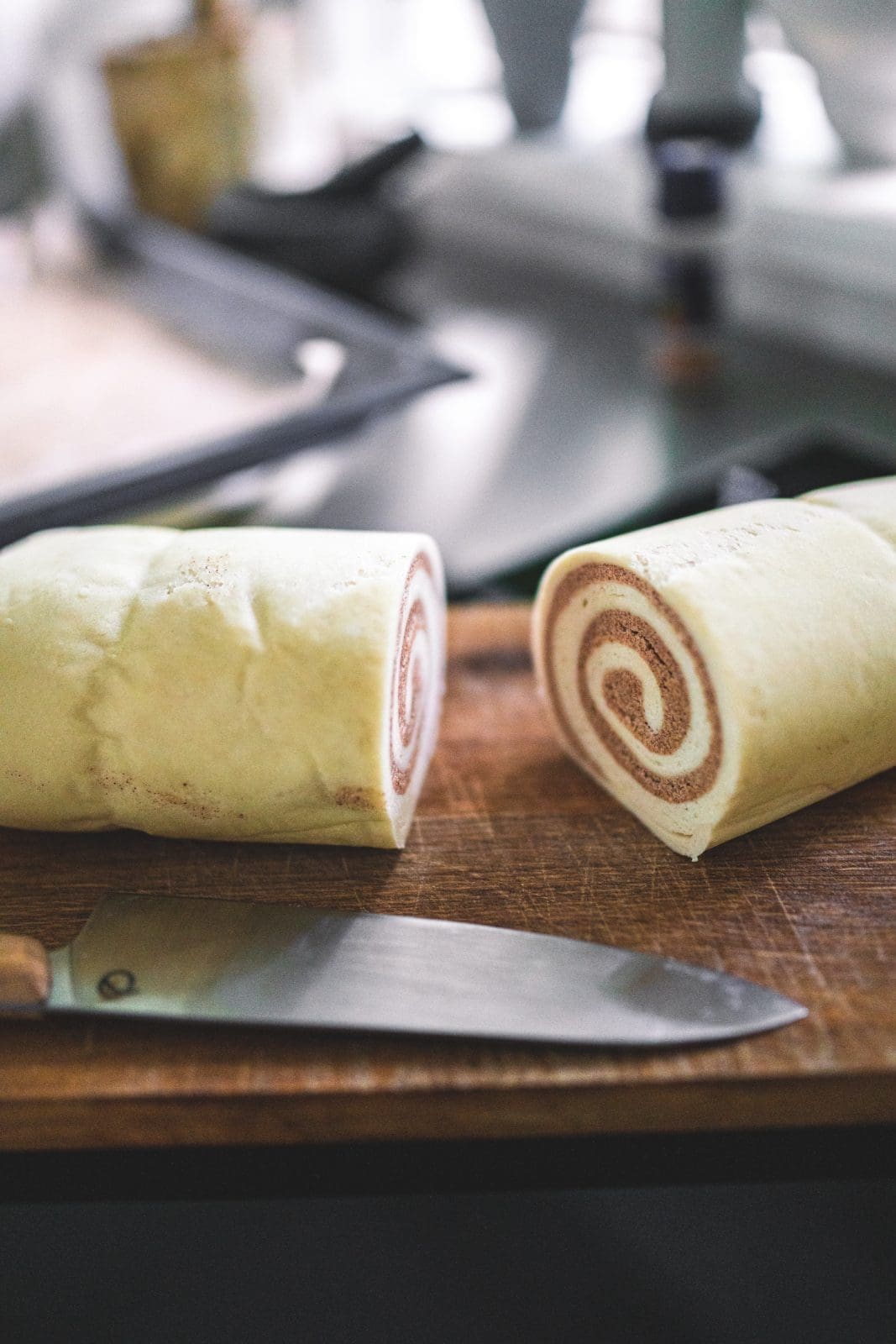 Aufgerollter Zimtschnecken-Teig wird in Scheiben geschnitten
