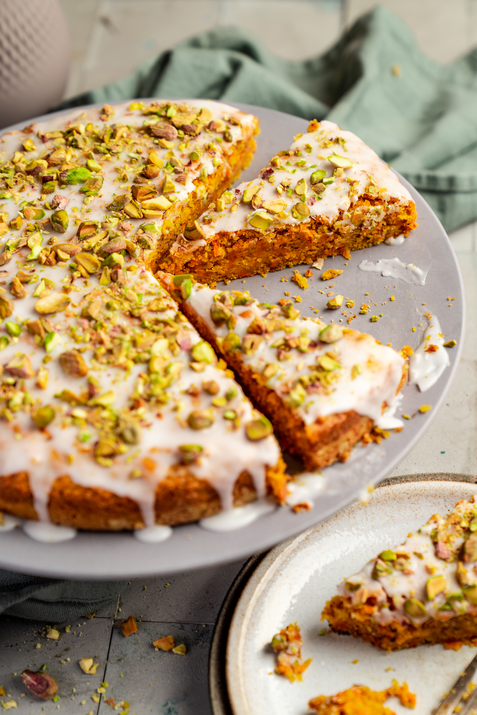 Moehrenkuchen Pistazie 2 | Seit wir uns mit der Eröffnung unseres Foodstudios Oma Lore einen kleinen Traum erfüllt haben, einen Ort zu schaffen, an dem wir arbeiten können und zusätzlich mit lieben Gästen gemeinsam in unserer Küche kochen zu dürfen, veranstalten wir immer wieder kleine Team Events. Manchmal bringen die Gäste ihre eigenen Rezepte mit, aber da wir ja mittlerweile einen schönen Fundus an Rezepten zusammen getragen haben, können die Gäste sich auch gerne hier auf dem Blog bedienen. Was uns zu einem Event im letzten Jahr fehlte, war ein veganes Dessertrezept, das zu einem orientalischen Abend passt. Gefunden haben wir Hacuv Pastasi oder auch orientalischer Karottenkuchen.