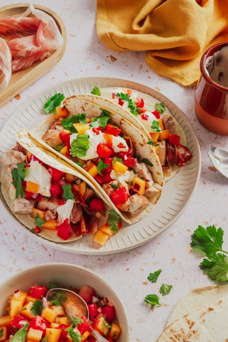 Hähnchen-Tacos mit knusprigem Parmaschinken und Melonensalsa auf einem Teller