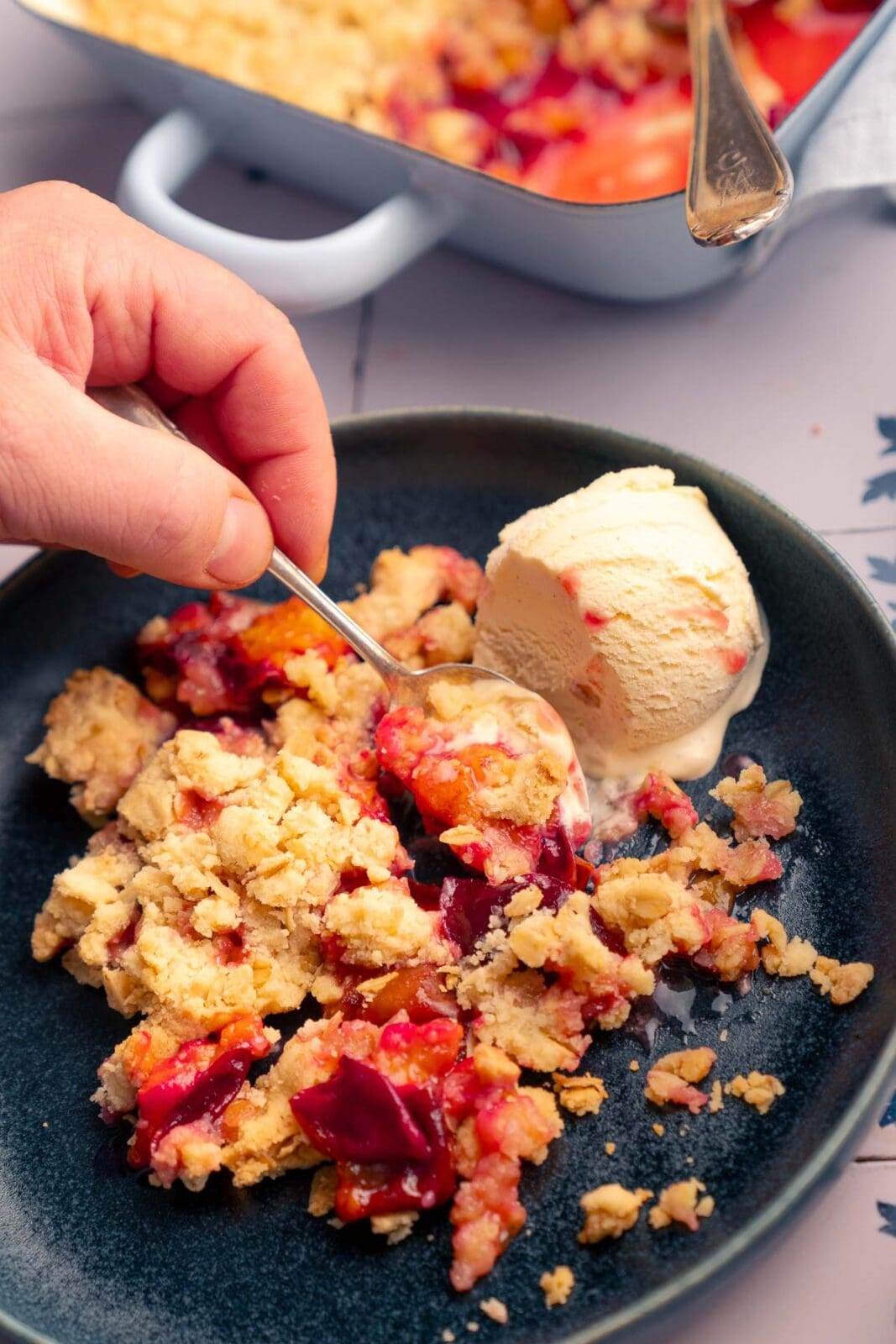 Zwetschgen-Crumble angerichtet auf Teller mit cremigem Vanilleeis