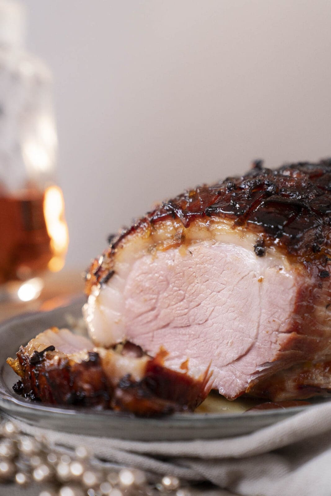Saftiger Krustenbraten mit knuspriger Schwarte und Orangen-Whisky-Glasur auf Servierplatte