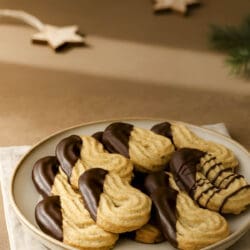 Spritzgebäck mit Haselnüssen – Mamas Familienrezept für Weihnachten 14 Schokoladenüberzogene Spritzgebäck mit Haselnüssen auf Teller