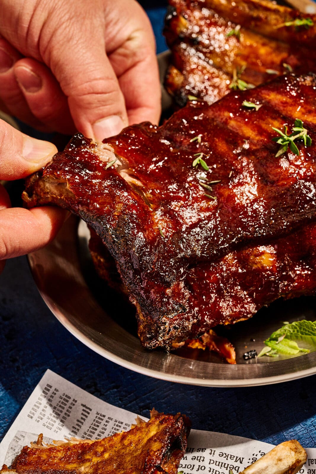 Saftige Spareribs auf dem Teller. Nahaufnahme. ein Rippchen wird abgezogen