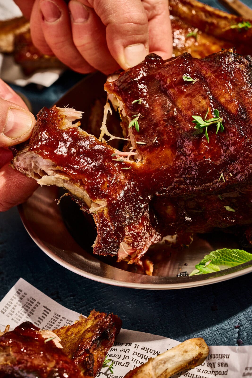 Saftige Spareribs auf dem Teller. Ein Rippchen wird abgezogen.