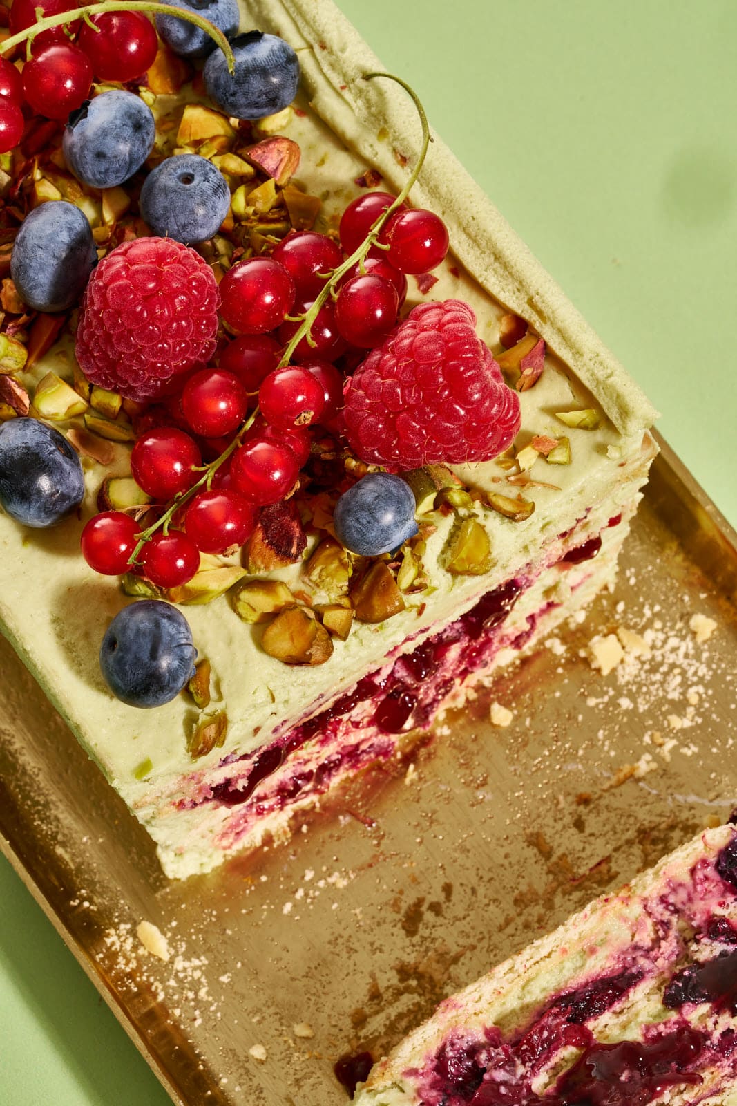 Pistazienkuchen ohne Backen mit Waldbeeren, getoppt mit Johannisbeeren, Heidelbeeren, Himbeeren und gehackten Pistazien