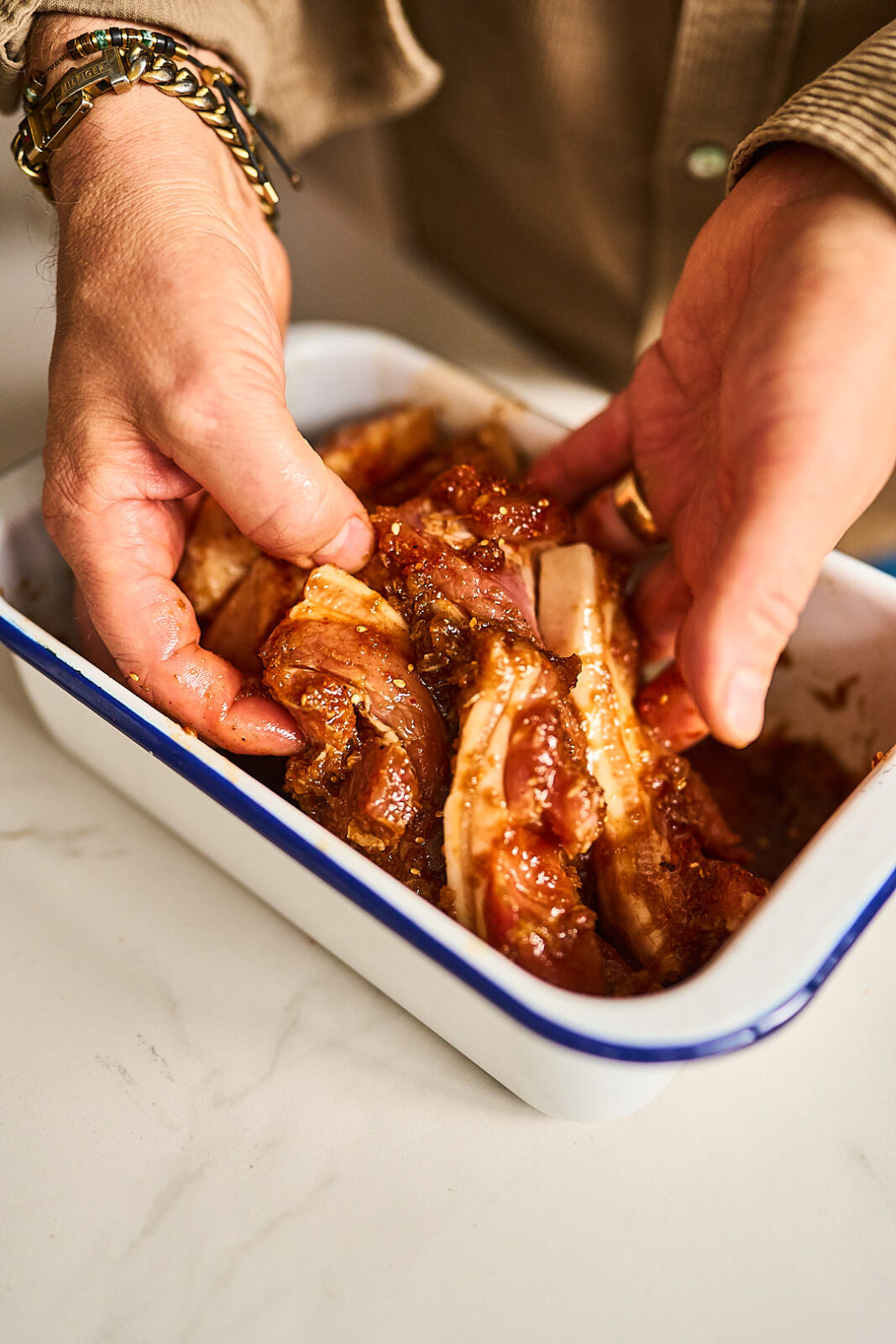 Schweinebauchstreifen mit den Händen in der Marinade wenden