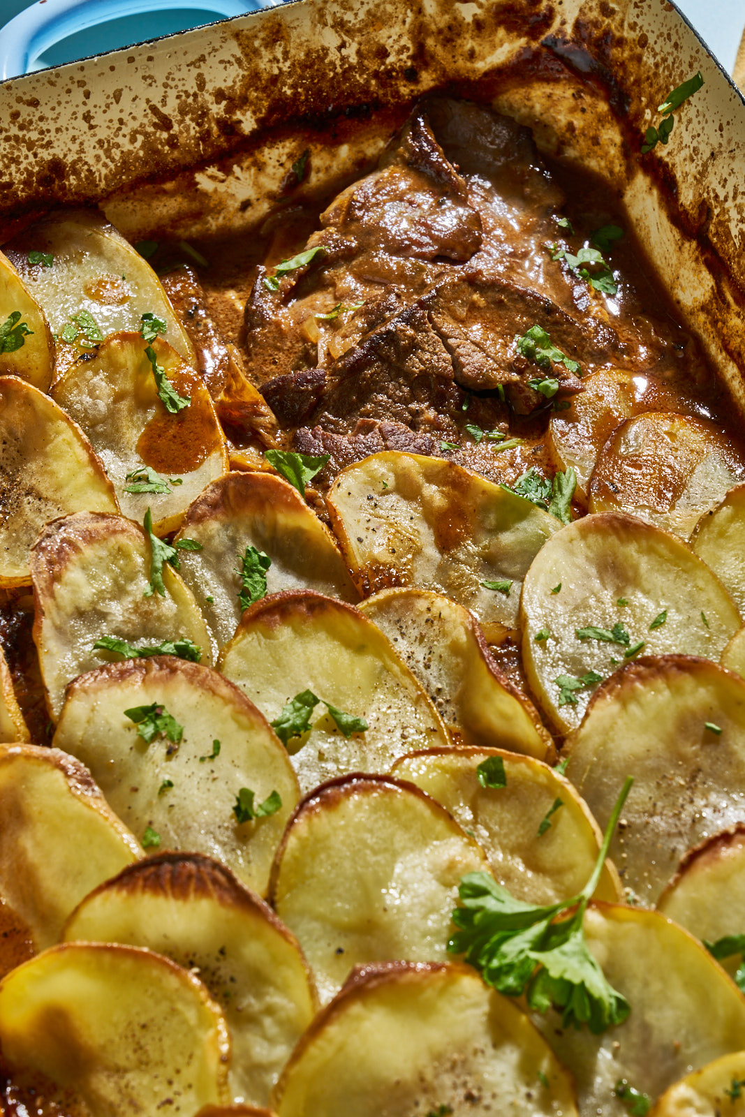 Nahaufnahme der knusprigen Kartoffeldecke auf dem Rouladen-Auflauf mit frischer Petersilie