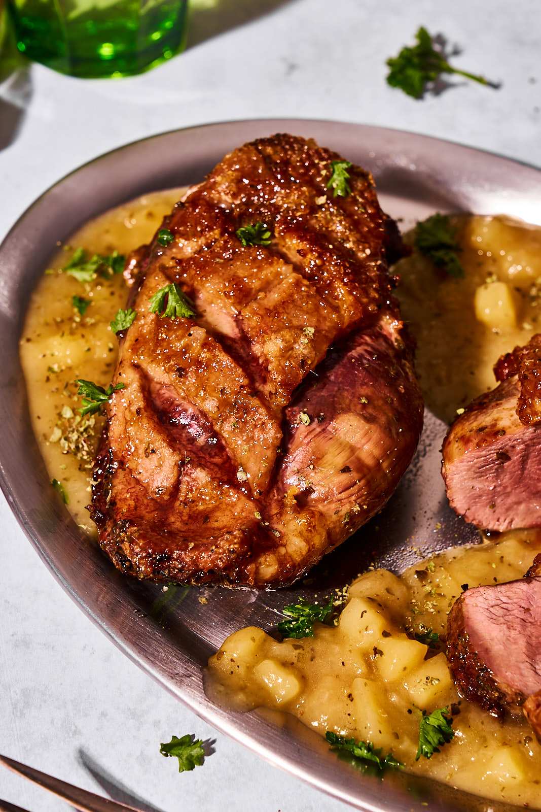 Ganze Gänsebrust mit knusprig gebräunter, eingeschnittener Haut auf Apfel-Honig-Jus