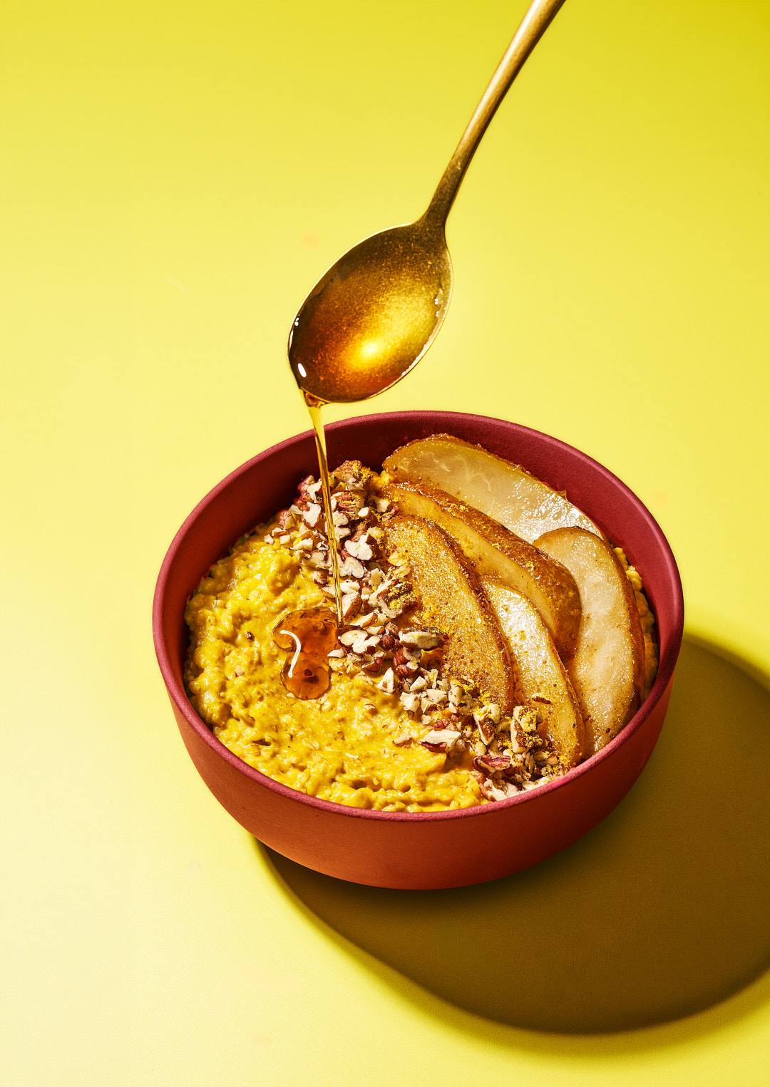 Pumpkin Spice Rezepte aus dem Adventskalender. Latte, Porridge und Kürbis-Muffins 7 Pumpkin Spice Porridge in roter Schale mit karamellisierten Birnenspalten, Pekannüssen und Ahornsirup vom Löffel