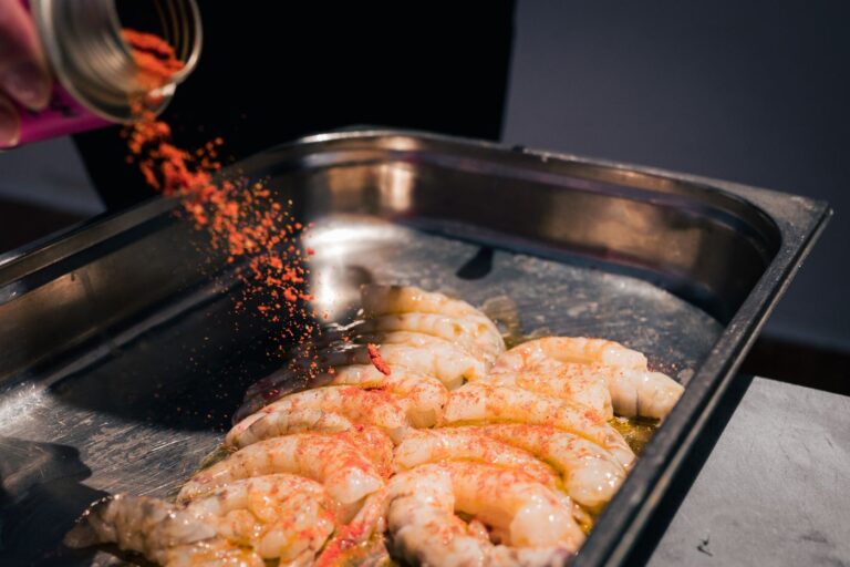 Gewürz von STAY SPICED ! wird aus der Dose über Garnelen in einer Grillschale gestreut