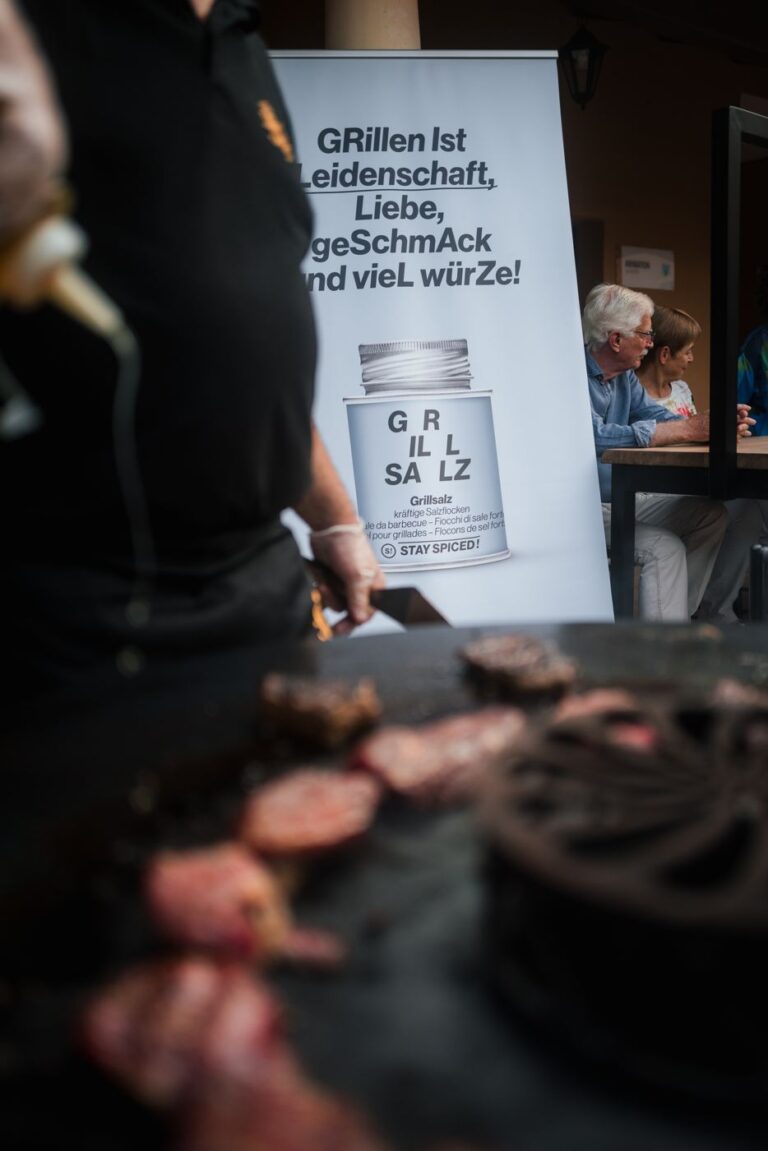 Aufsteller für das Grillsalz von STAY SPICED ! hinter einer Feuerplatte mit Steaks beim Gourmetgipfel 2023